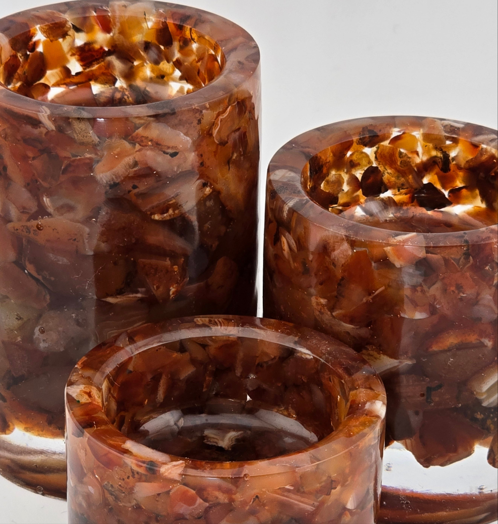 Three Carnelian semi-precious gemstone tea light candle holders on a white background. Close-up