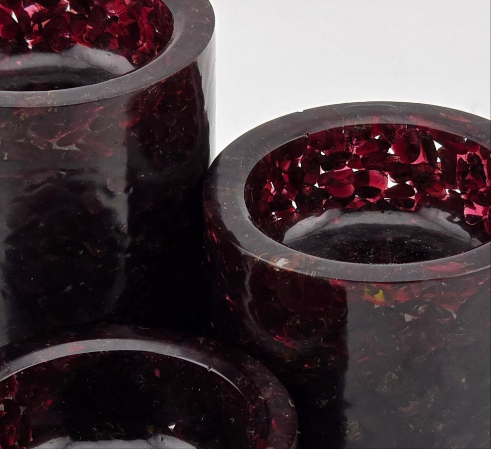 Close-up of dark red garnet gemstone tea light candle holders on a white background.