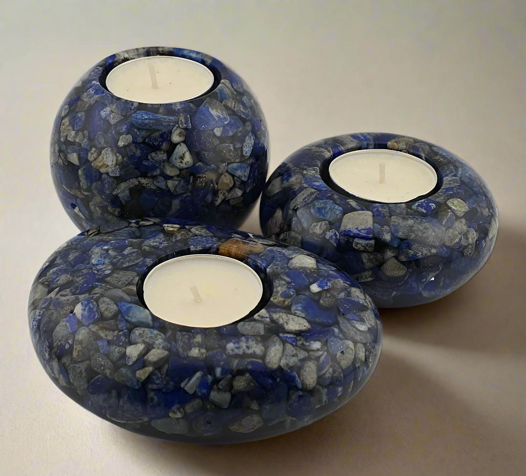 Three blue and gray Lapis Lazuli tea light candle holders with candles on a neutral background