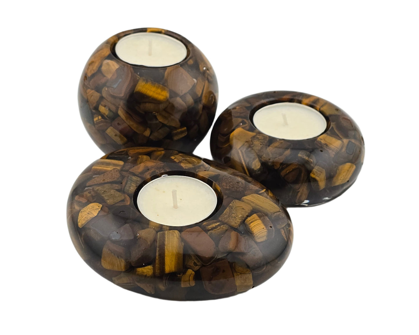 Three tiger eye stone candle holders with white candles on a light gray background