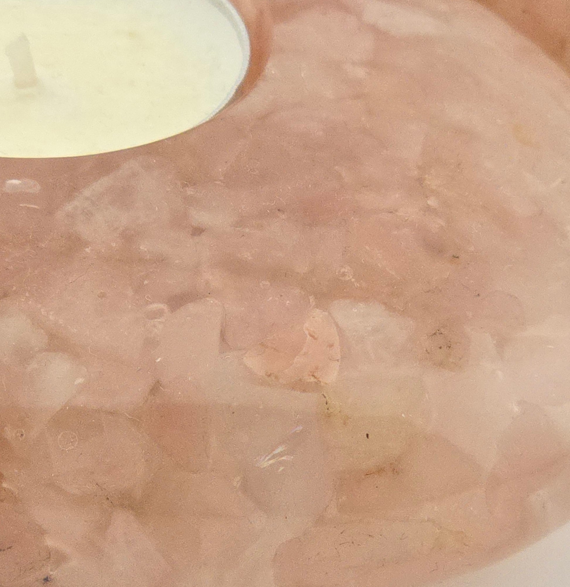 Close-up of a textured beige surface with a white container in the corner.