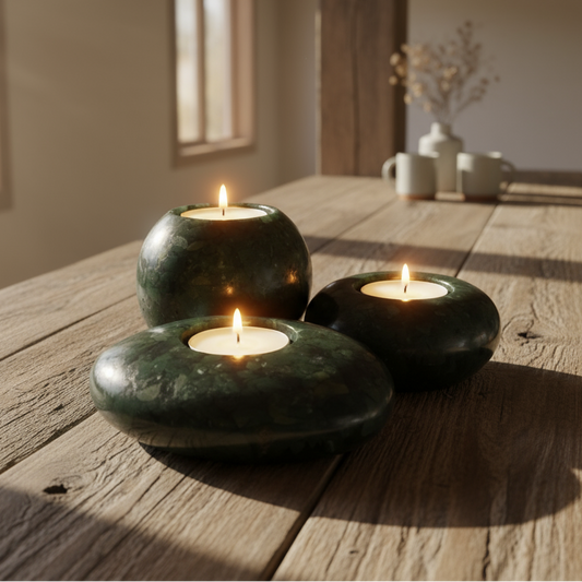 Three green Aventurine candle holders with lit candles on a wooden table.
