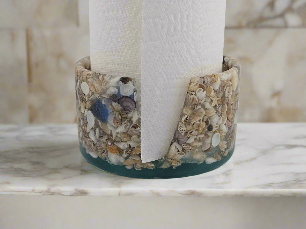 Paper towel holder made of seashells, starfish, sea glass, and resin on a marble surface